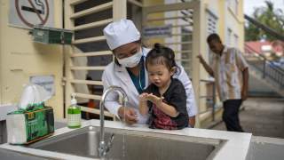 A doctor at Kirivong Referral Hospital, Cambodia, shows her daughter how to wash her hands at a UNICEF-supported handwashing station.